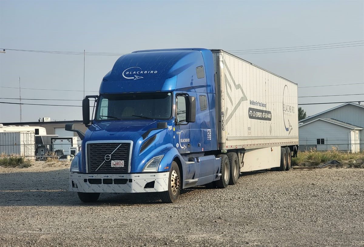 Blue Blackbird sleeper tractor, unit 761, with a dry van trailer ready for a Canada–U.S. run